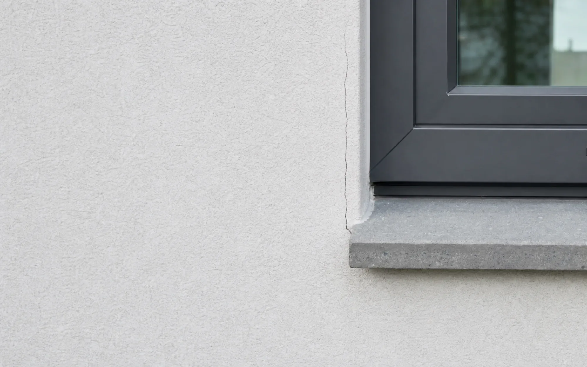 Feiner Riss im Außenputz neben einem Fensteranschluss